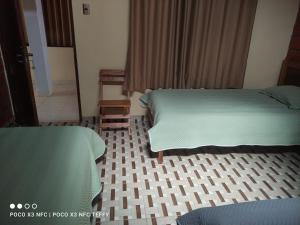 Habitación de hotel con 2 camas y suelo de baldosa. en Casa Hotel Vida Caranavi, La Paz, en Caranavi