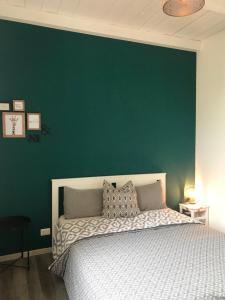 a bedroom with a green wall and a bed at Mazzini apartment in Arona