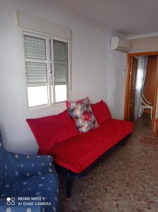 - un canapé rouge dans une chambre avec fenêtre dans l'établissement habitación turquesa, à Barbate