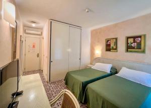 una camera d'albergo con due letti e un tavolo di Hotel Meridiana a Marina di Campo