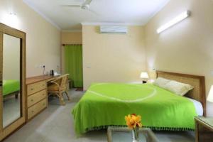 a bedroom with a green bed and a desk and a mirror at Cox's Bazar Surf Club Resort & Cafe in Cox's Bazar