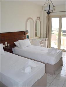 two beds in a hotel room with towels on them at La Luna Apartments in Stalida