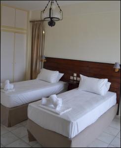 2 Betten in einem Hotelzimmer mit weißer Bettwäsche in der Unterkunft La Luna Apartments in Stalida