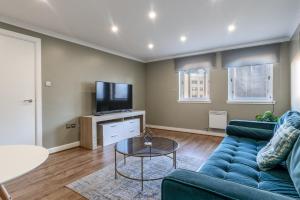 a living room with a blue couch and a tv at ** Modern Merchant City 1 BED Apartment with Free Parking ** in Glasgow
