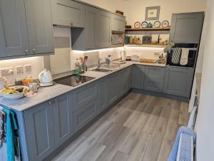 a large kitchen with gray cabinets and wooden floors at Cliffside is a Cosy Cottage B&B by Cowes Beach - Very big King Size guest BR & a Twin BR too if you book 3 to 4 guests in Cowes