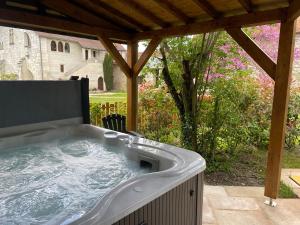 a hot tub under a pergola in a backyard at Le Cottage d'Eleanor gîte de charme avec spa Jacuzzi privé in Marçay