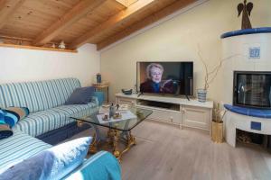 a living room with a couch and a tv at Attico con vista sul lago e montagne a Molveno in Molveno