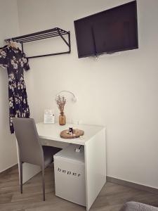 a white desk with a chair and a tv on a wall at DOMOBLU Camere In Centro in Tortolì