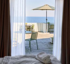ein Schlafzimmer mit Blick auf eine Terrasse mit einem Sonnenschirm in der Unterkunft Hotel Klippen in Gudhjem