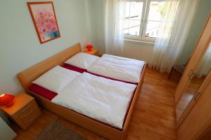 a bedroom with a bed with white sheets and a window at Ferienwohnung Nagoldtalblick in Nagold