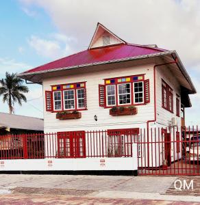 a white house with red windows and a red fence at Queen Maxima by Prins Hendrik Suites in Paramaribo