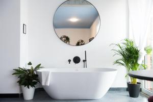 a bathroom with a white tub and a round mirror at Le Terrazze del Duca San Pietro Guesthouse in Rome