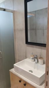 bagno con lavandino bianco e specchio di Studio Evridiki a Georgioupolis