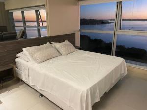 a bedroom with a white bed with a large window at Loft com vista incrível no Barra Shopping in Porto Alegre