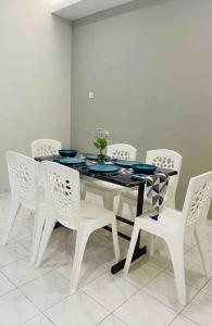 a dining room table with white chairs and a table with blue plates at The White House Near Heritage Jonker Malacca Town in Melaka