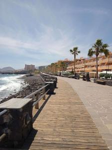 una passerella lungo una spiaggia con panchine e palme di Caletillas Beach Apartment a Santa Cruz de Tenerife