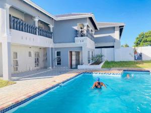 a man in a swimming pool in front of a house at Xaba Guest Lodge in Richards Bay