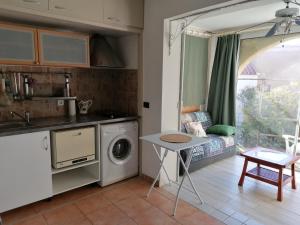 a kitchen with a washing machine and a table at Charmant 3 pièces terrasse climatisé bord de mer in Lumio +21 photos