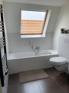 a bathroom with a white tub and a toilet at Casa Vista Verde in De Panne