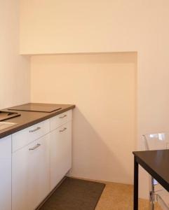 a kitchen with white cabinets and a table and a counter at Relais Flora Arzo Appartamento superior di vacanza con posteggio in Mendrisio