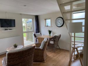 a dining room with a table and a clock on the wall at Appartement Zandwerven 23 in Spanbroek