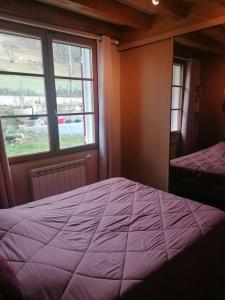 une chambre avec un lit violet et une fenêtre dans l'établissement Maison de charme Nature et Rivière au pays basque, à Estérençuby