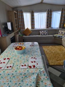 a living room with a table with a bowl of fruit on it at Caravan By The Sea in Elgin