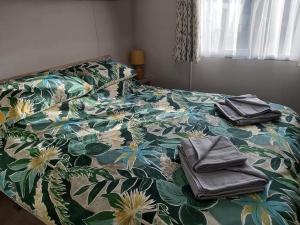 a bedroom with a bed with a floral bedspread and towels at Caravan By The Sea in Elgin