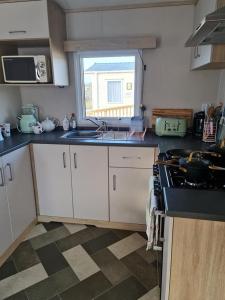 a kitchen with white cabinets and a sink and a window at Caravan By The Sea in Elgin