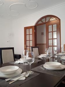 a dining room table with white plates and wine glasses at Chalas place in Nazaré