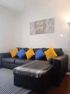 a black couch with yellow and blue pillows on it at Chalas place in Nazaré