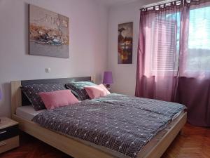Schlafzimmer mit einem Bett mit rosa Kissen und einem Fenster in der Unterkunft City Center in Labin