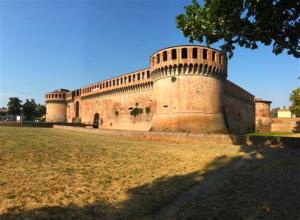 a large brick building with a tree in a field at Karibu b&b in Imola