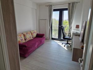 ein Wohnzimmer mit einem lila Sofa und einem Balkon in der Unterkunft Apart Confort in Bacău