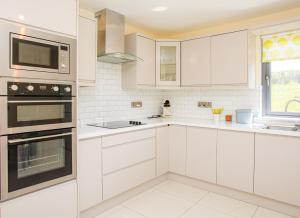 a white kitchen with white cabinets and a window at Lakeview Waterville Holiday Home in Waterville