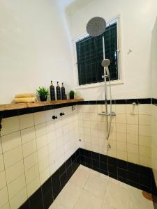 a shower in a bathroom with black and white tiles at Queen Maxima by Prins Hendrik Suites in Paramaribo