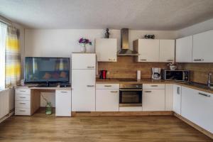 a kitchen with white cabinets and a tv in it at Ferienwohnungen Hubner 1 am Flattachberg in Flattach