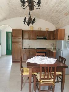 uma cozinha com uma mesa com cadeiras e um frigorífico em Trullo Le Tre Sorelle em Cisternino