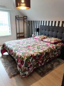 a bedroom with a bed with a floral bedspread at CHEZ HÉLÈNE in Saint-Coulomb
