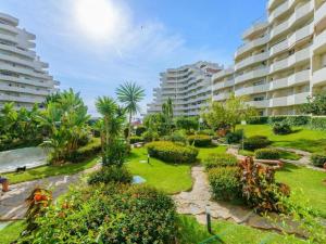 a garden in front of a large apartment building at BenalBeach Yasmine in Benalmádena