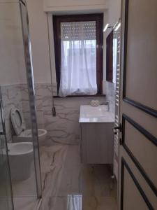 baño con lavabo y aseo y ventana en Appartamento Le Rose, en Viareggio
