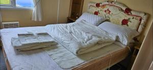 a large bed with white sheets and pillows on it at Oor wee hoose in Leswalt