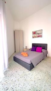 1 dormitorio con 1 cama con almohadas rosas y moradas en CASA ROSINA, en SantʼAntìoco