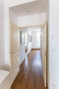 um corredor com paredes brancas e piso de madeira em Proche Panier, appartement cosy vue mer em Marselha