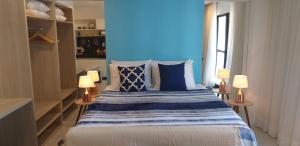 ein Schlafzimmer mit einem Bett mit blauen Wänden und 2 Lampen in der Unterkunft Edf Time Ponta Verde, Studio 523 in Maceió
