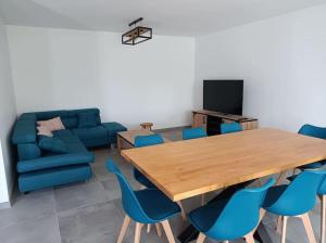een woonkamer met een houten tafel en blauwe stoelen bij Villa Côté Charance Pelleautier in Pelleautier