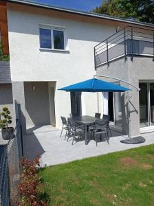 een patio met een tafel en stoelen en een blauwe parasol bij Villa Côté Charance Pelleautier in Pelleautier