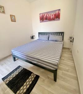 a bed in a bedroom with a painting on the wall at Torre dei Corsari APPARTAMENTO CON GIARDINO VISTA MARE in Torre Dei Corsari