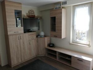 a living room with a tv and wooden cabinets at Ferienwohnung auf Rügen in Putbus