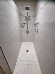 ein weiß gefliestes Bad mit einer Dusche mit einem Abfluss in der Unterkunft Grande Villa familiale et chaleureuse à Saulieu in Saulieu